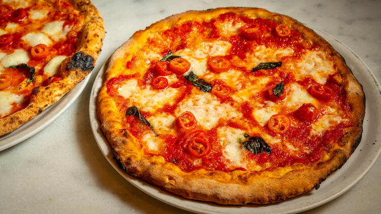 Two Neopolitan pizzas on a marble table