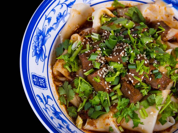 Bowl of noodles topped with beef and herbs