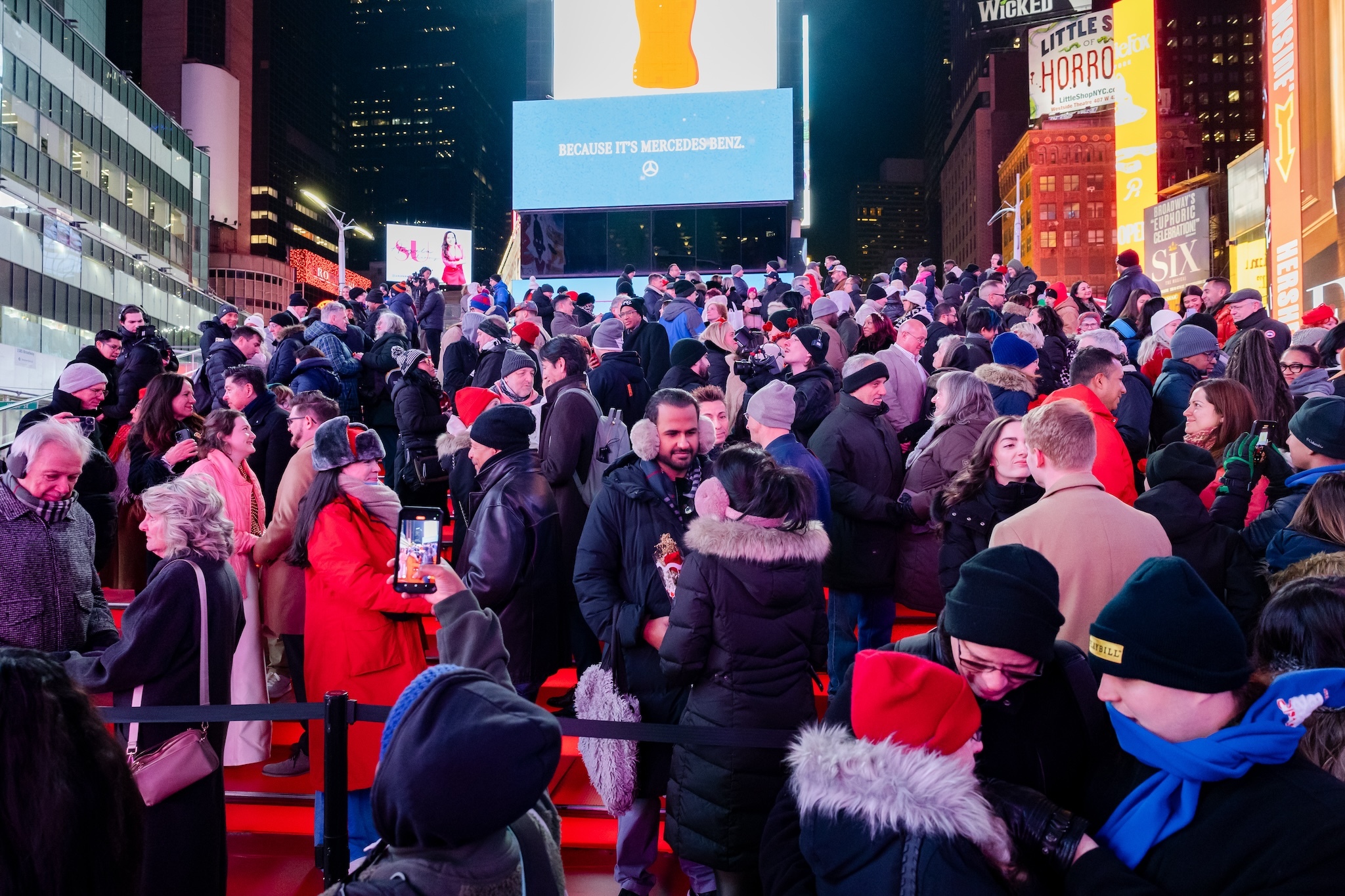 A group of couples stand on the red steps in Times Square to renew their vows.