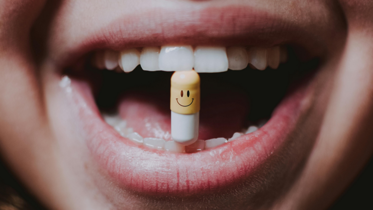 A face with a (smiley-face) pill in her mouth.