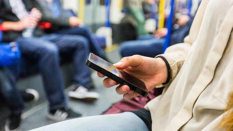 A photograph of someone using a phone on an underground train