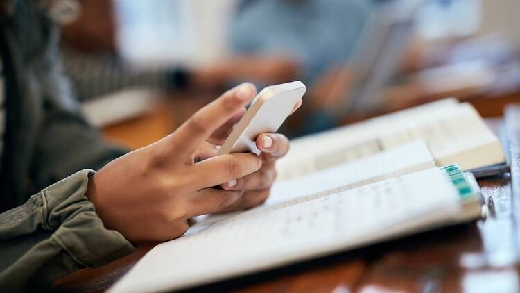 A photograph of someone using a smartphone at a desk