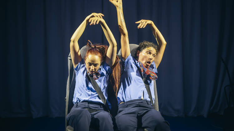 Two people strapped into seats with their arms in the air.