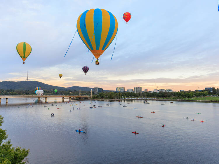 Hot air balloons floating over lake