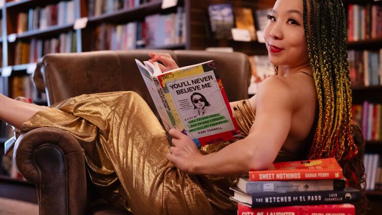 A woman sits in a leather chair holding a book.