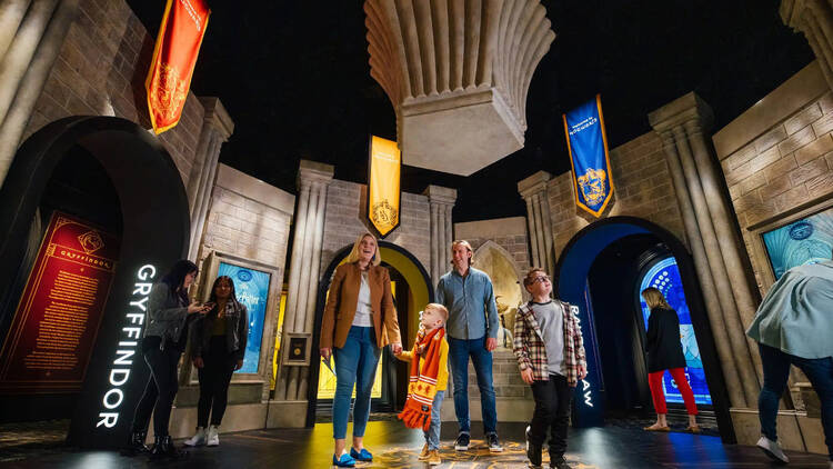 People inside a Harry Potter themed room with the Hogwarts house emblems