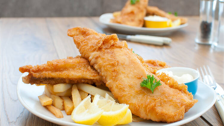 A photograph of fish and chips on a plate with a slice of lemon