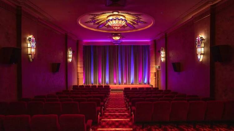 Movie theatre with red seats and neon lights on stage