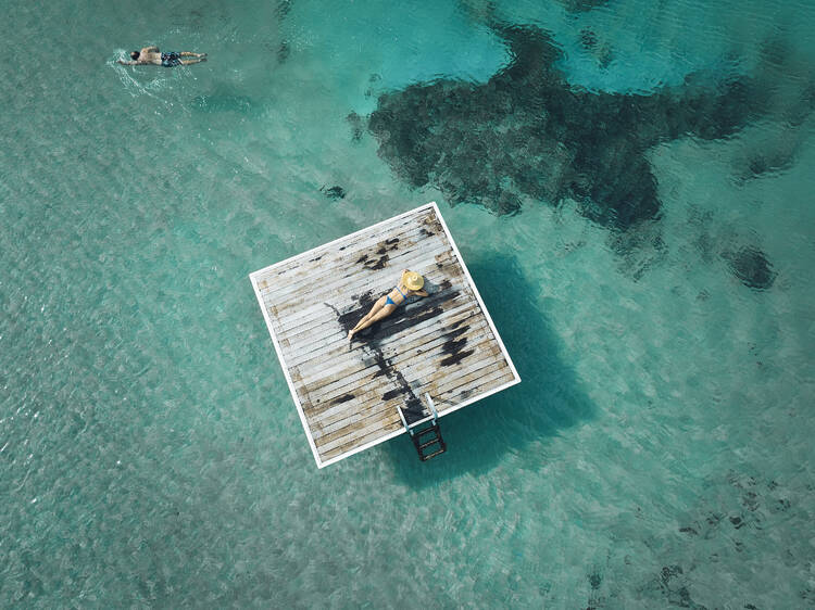 Aerial shot of lady sunbaking on pontoon in middle of water