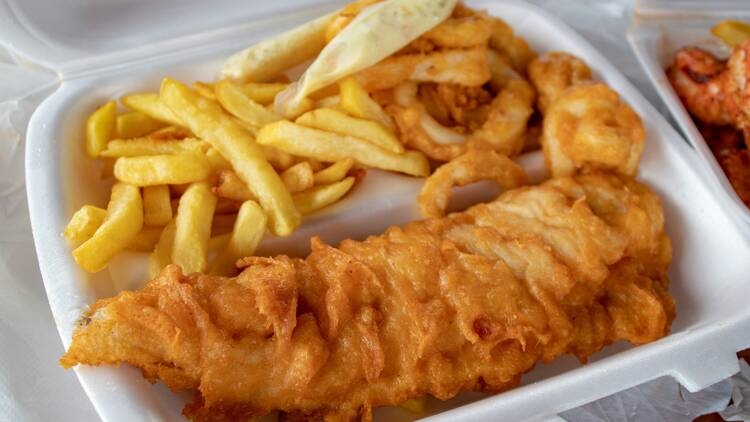 Battered fish with chips in takeaway box