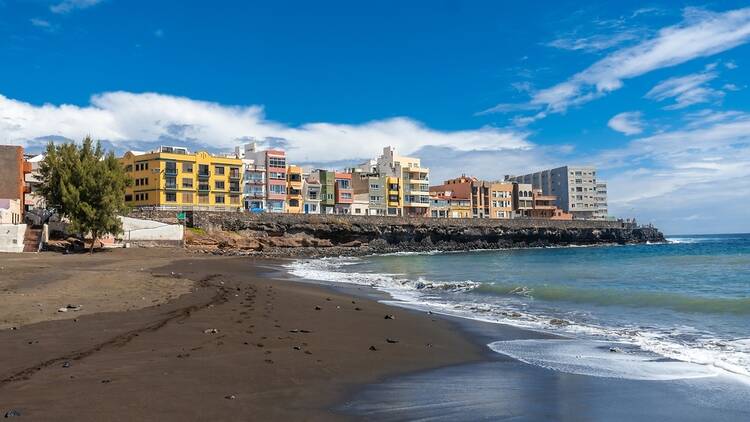 Black sand beach with colourful houses in Telde, Gran Canaria