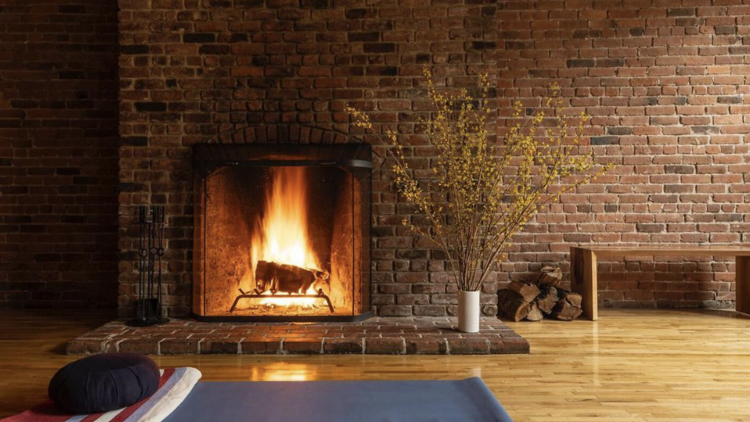 A fireplace with a roaring fire next to a yoga mat.