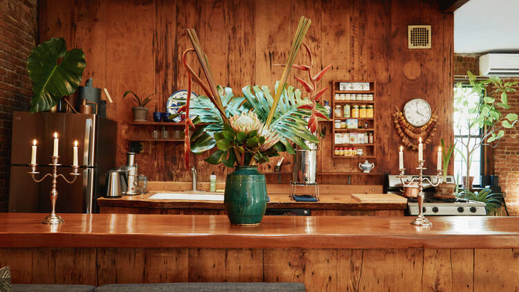 A kitchen scene with wooden paneling and a large vase of flowers.