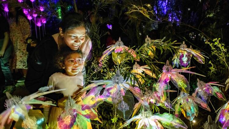 A mother and daughter looking at a glowing floral artwork. 