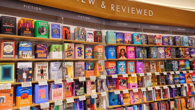 A large shelf filled with books, with the words 'New and Reviewed' above it. Each book has a small handwritten note underneath it. 