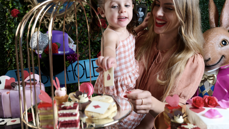 Mum and daughter eating Alice in Wonderland-themed high tea snacks