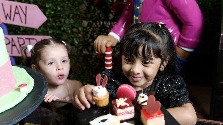 Girl eating Alice in Wonderland-themed high tea snacks