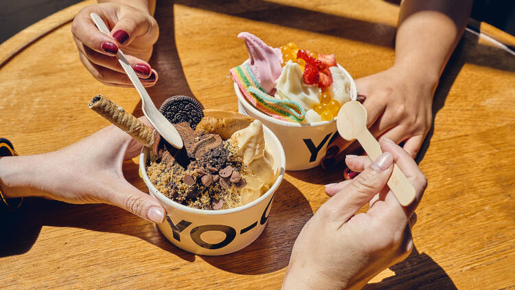 Two pots of frozen yogurt with toppings