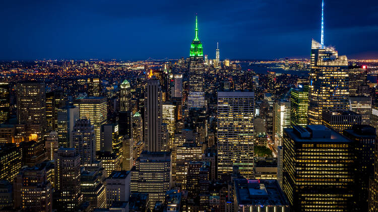 The NYC skyline with the Empire State Building lit up in green.