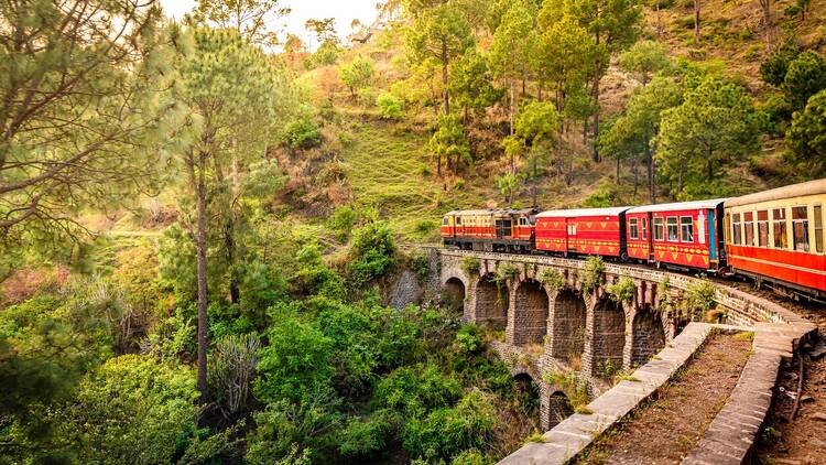 View from moving train on arch bridge over mountain slopes, beautiful view, one side mountain, one side valley. Toy train from Shimla to Kalka in Himachal Pradesh, India