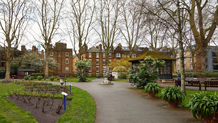 A concrete pathway alongside flower patches in Paddington Street Gardens, Marylebone