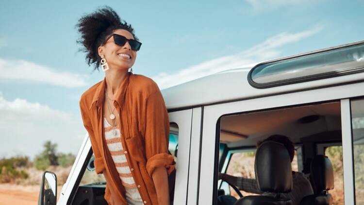 Woman enjoying window view of desert and traveling in jeep on holiday road trip of South Africa