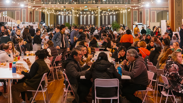 A room filled with people sitting at tables. 