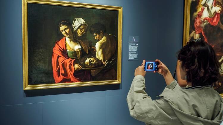 A tourist takes a photo of a Caravaggio painting