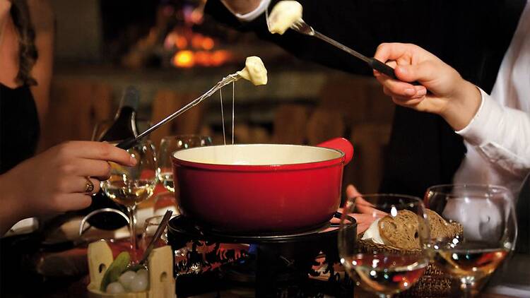 People dipping in cheese fondue. 