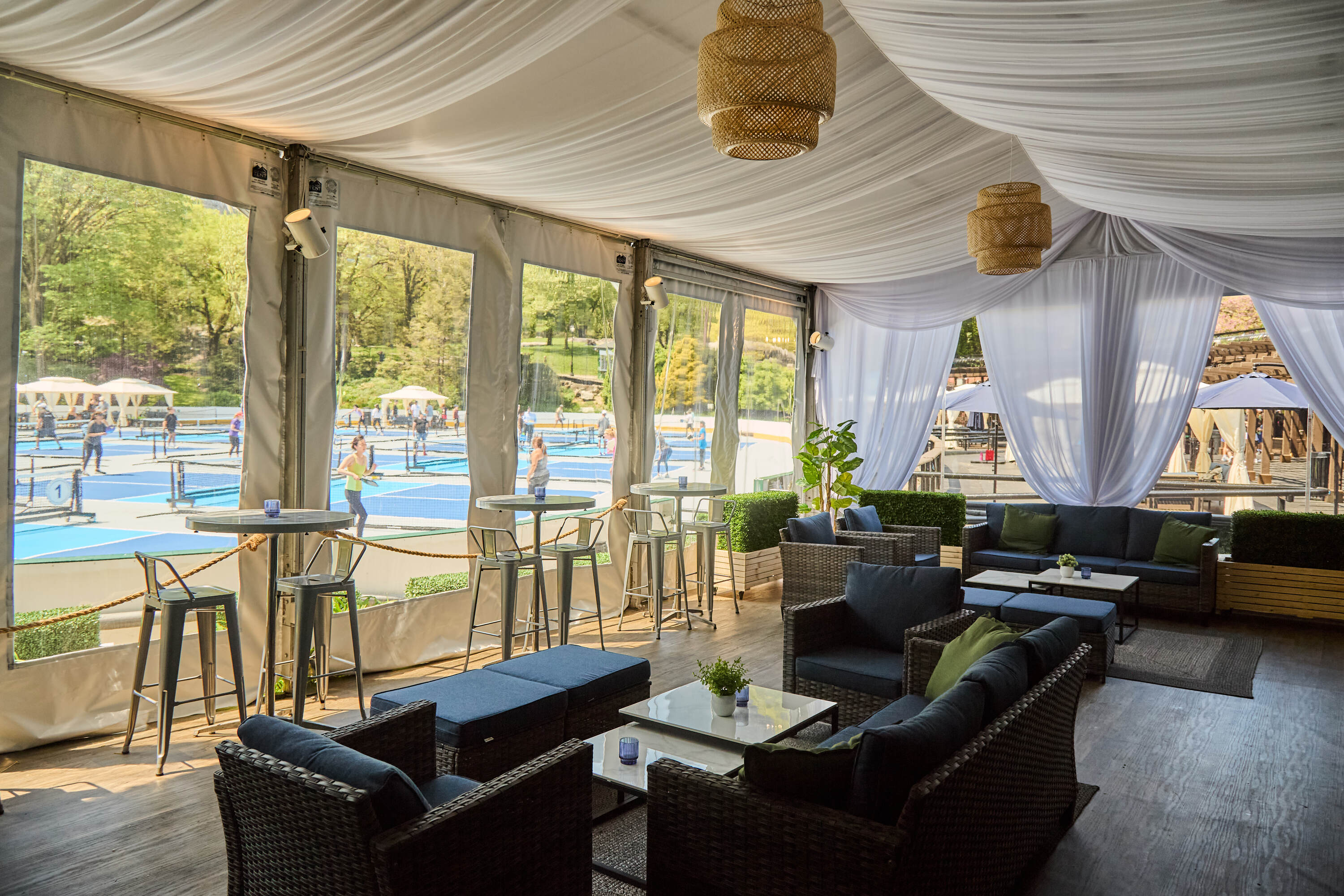 A cabana with blush couches and views of pickleball courts.