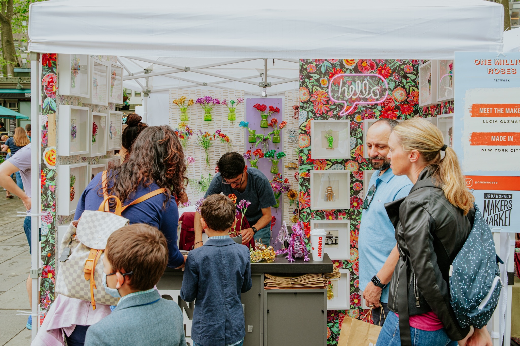 A family looks at wire flowers in a booth at a vendor market.
