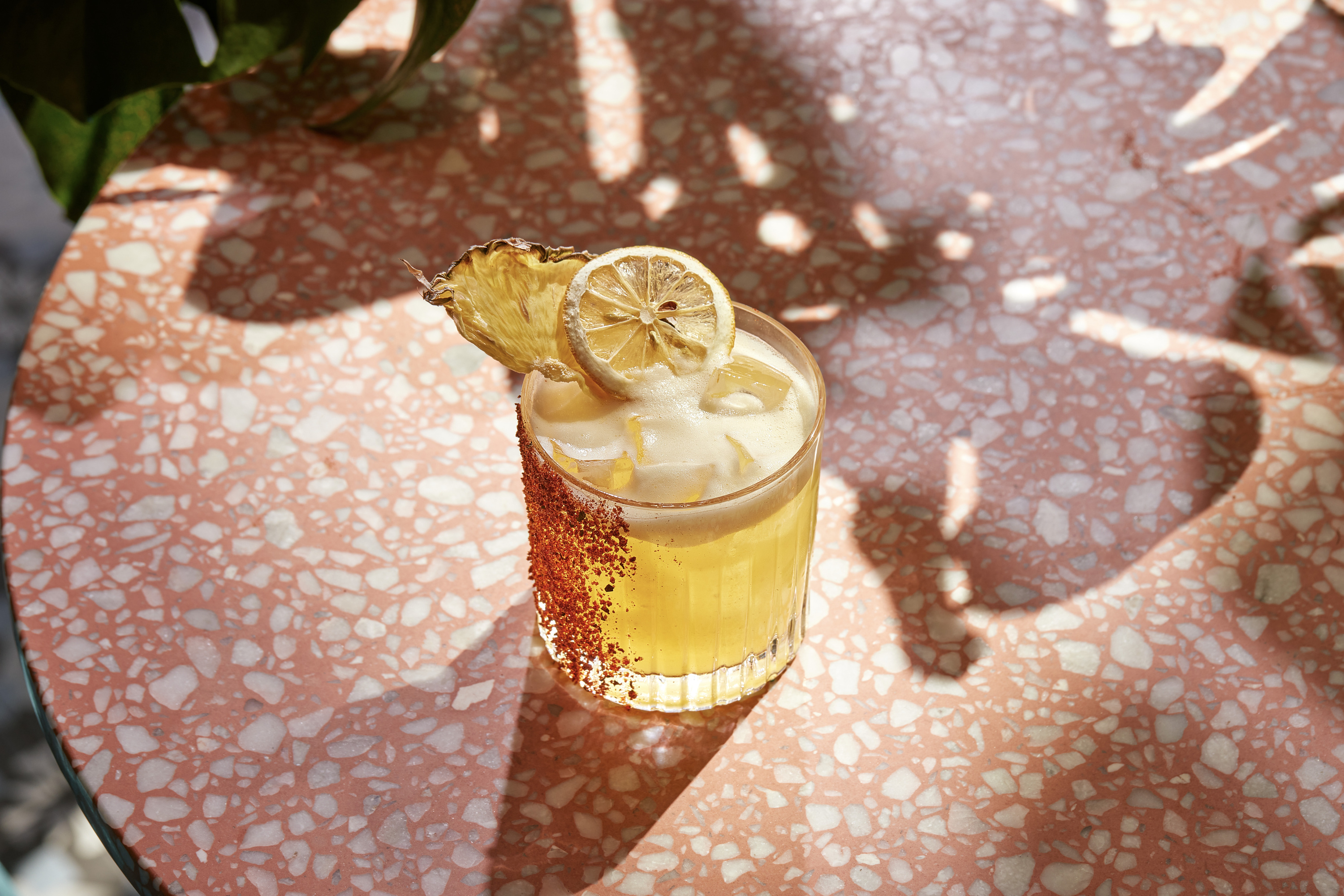 Your Mother’s Spritz at Virgin Hotels is a yellow drink in a tajin-covered low glass with desiccated pineapple and lemon to garnish