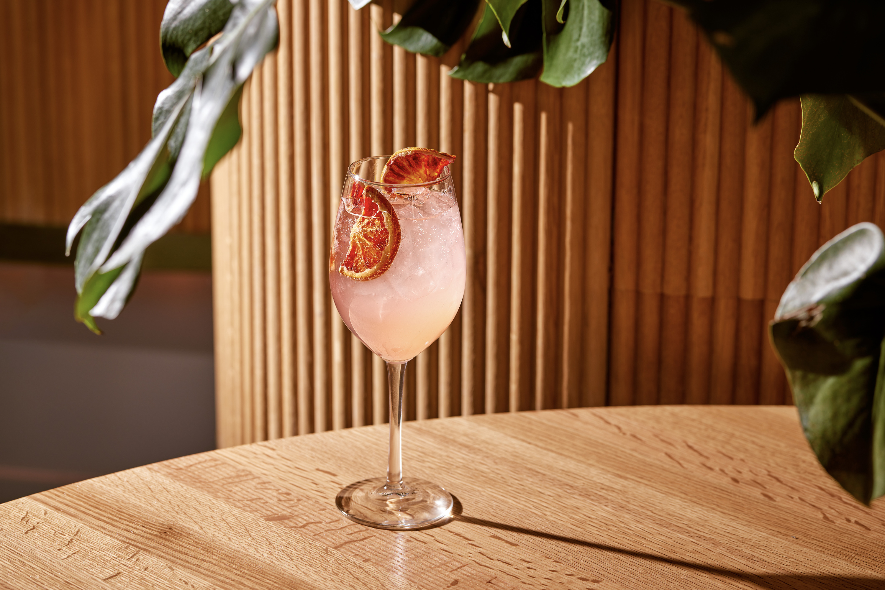 Palm Springs Punch at Virgin Hotels is a pink drink in a wine glass with grapefruit slices