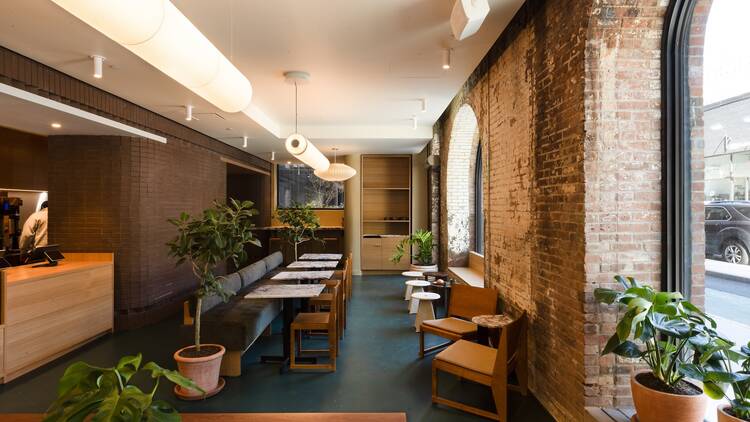Brick and wooden walls and a long interior with marble tables and wooden chairs