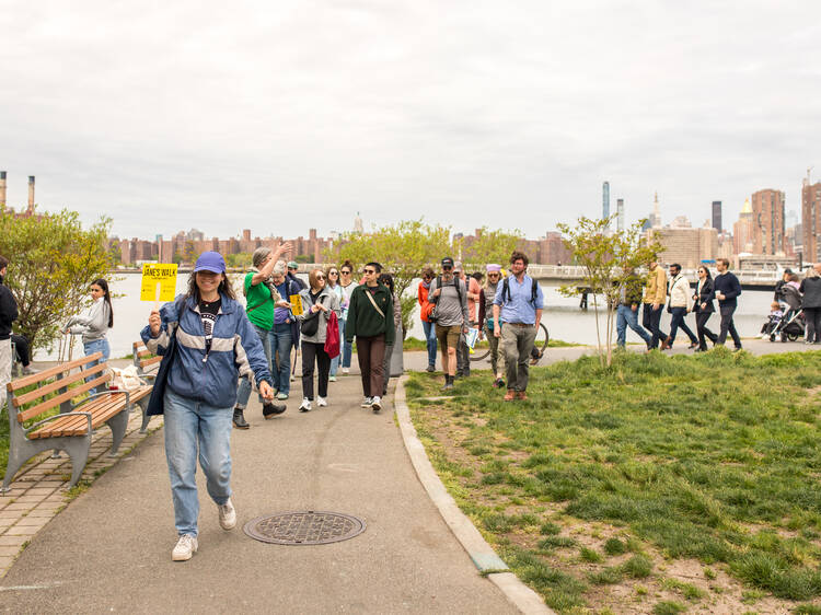 A woman holds up a yellow sign while leading a group of people on a walking tour.