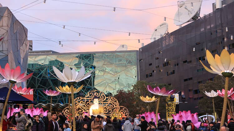 Giant illuminated lotus flowers and a statue of Buddha. 