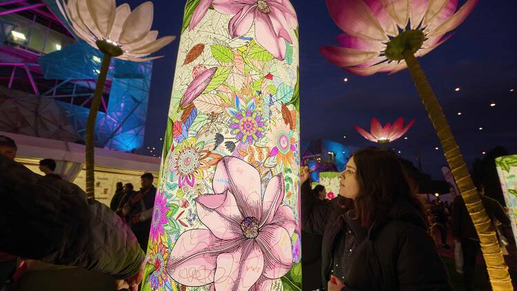 A person looking at an illuminated artwork. 