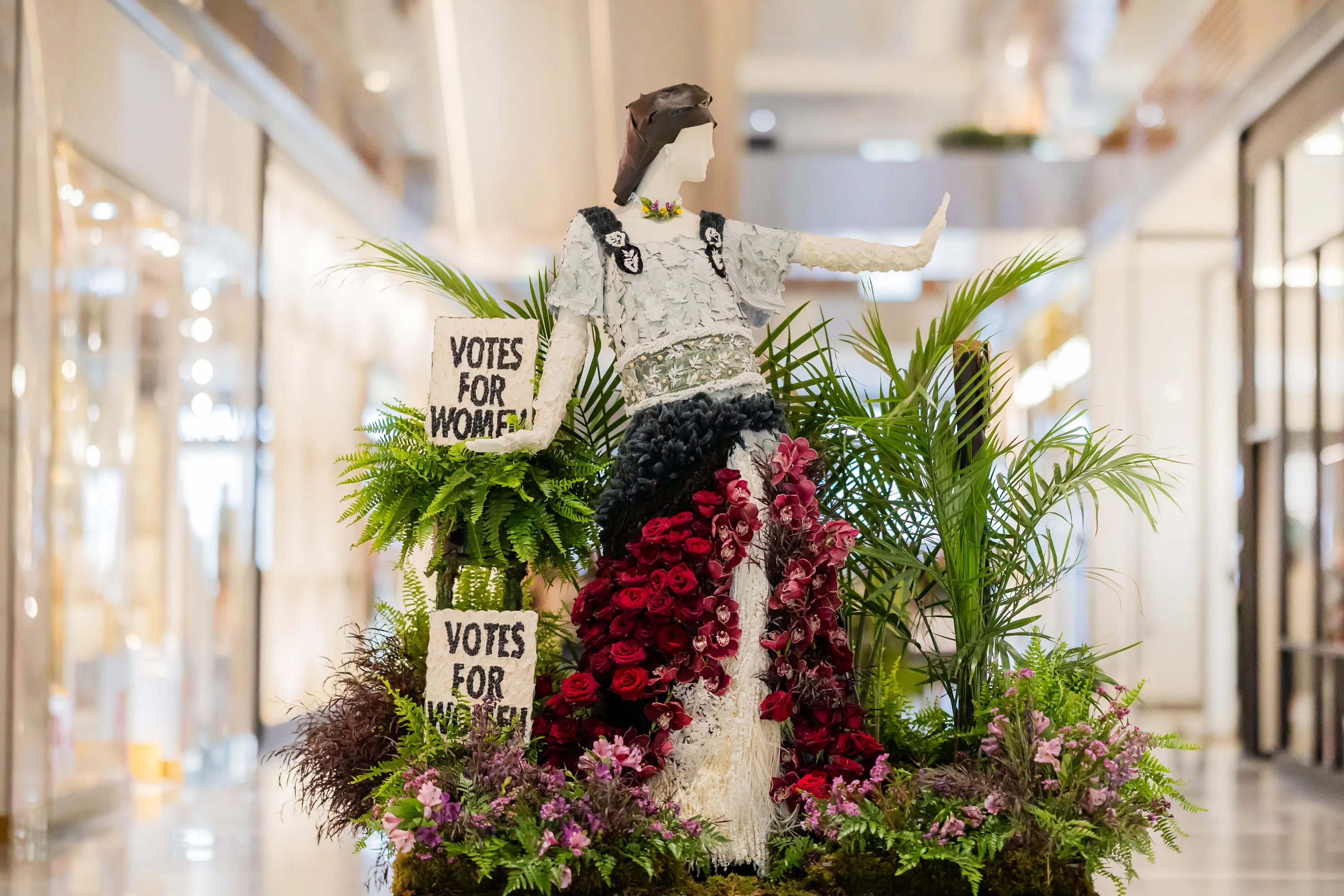 A floral mannequin of a woman in a white and red dress.