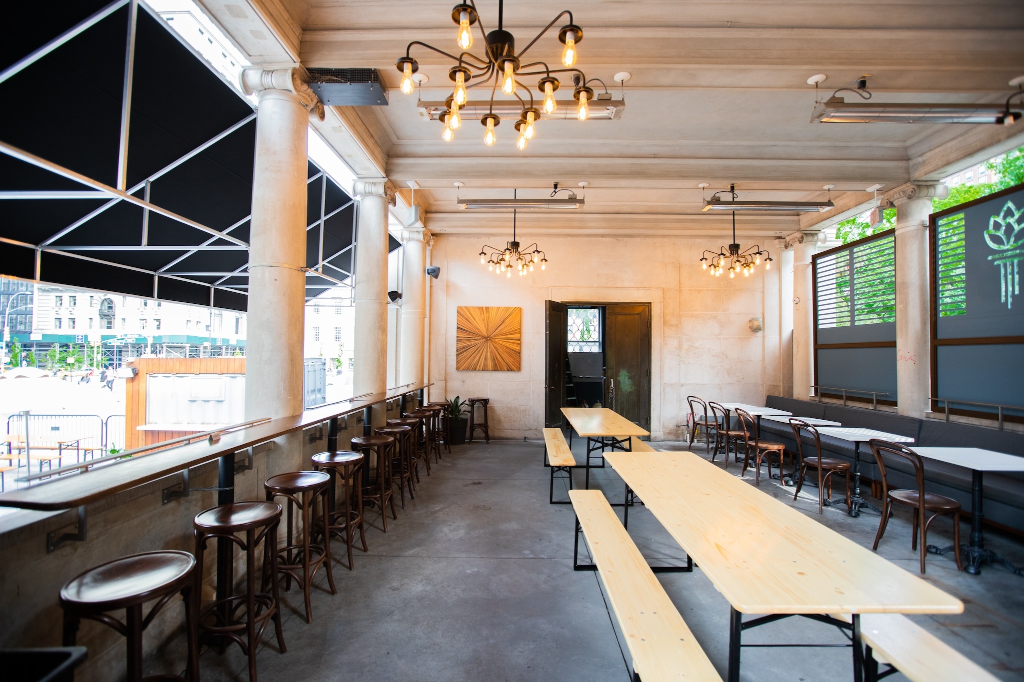 Long wooden tables and chandeliers inside the Torch & Crown Beer Garden