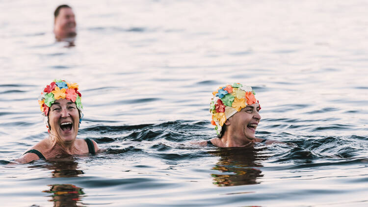 Two women in floral swim caps doing the Solstice Swim as part of the East Gippsland Winter Festival.