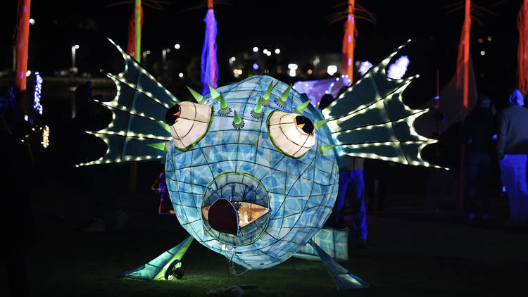 A large glowing coloured lantern in the shape of a fish.