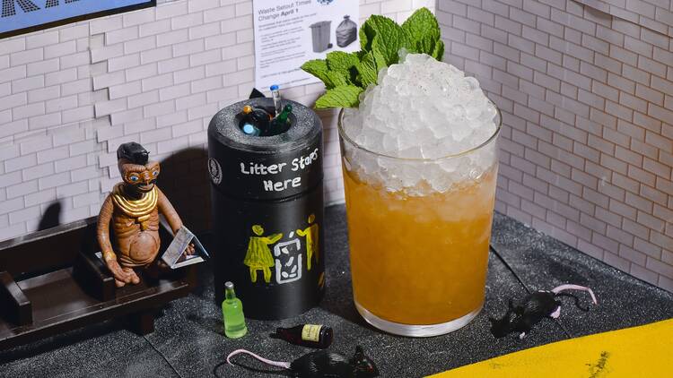 | Van Cortlandt Park cocktail with ice and mint. Pictured in a mini diorama of the train system