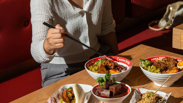 Woman enjoying sitting down to a lunch of Taiwanese street food favourites.