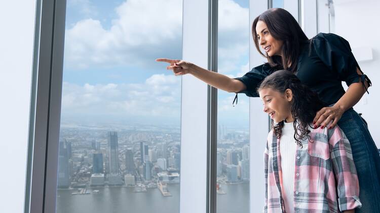 | A woman and a child looking out at the views of One World Observatory