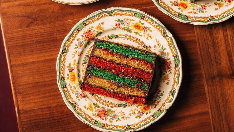A slice of rainbow cake on a decorative plate