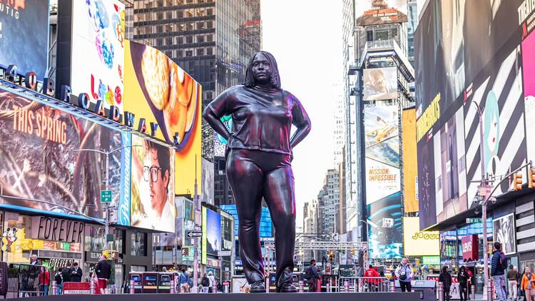a bronze statue of a girl in Times Square
