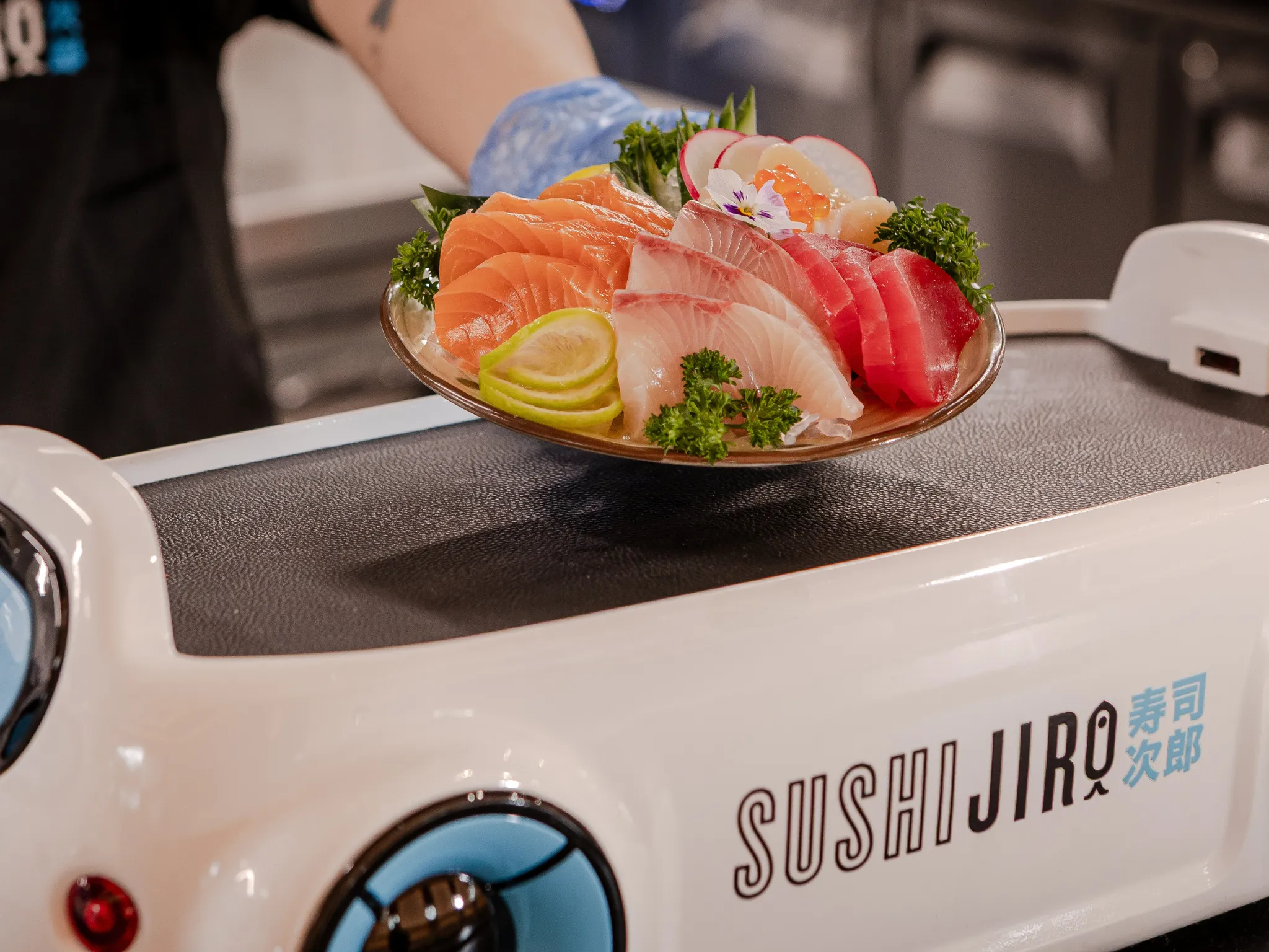 Staff member presenting a dish of sashimi.