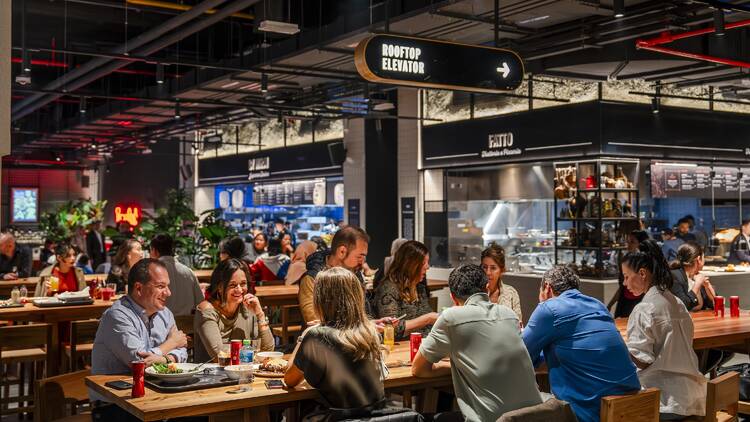 Tables of people talking and eating at Time Out Market Bahrain