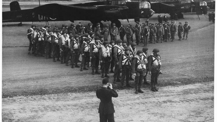 A photographer taking a photograph of a unit of paratroopers in front of an aircraft at RAF Ringway