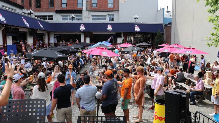 A group of people outside under various colored umbrellas